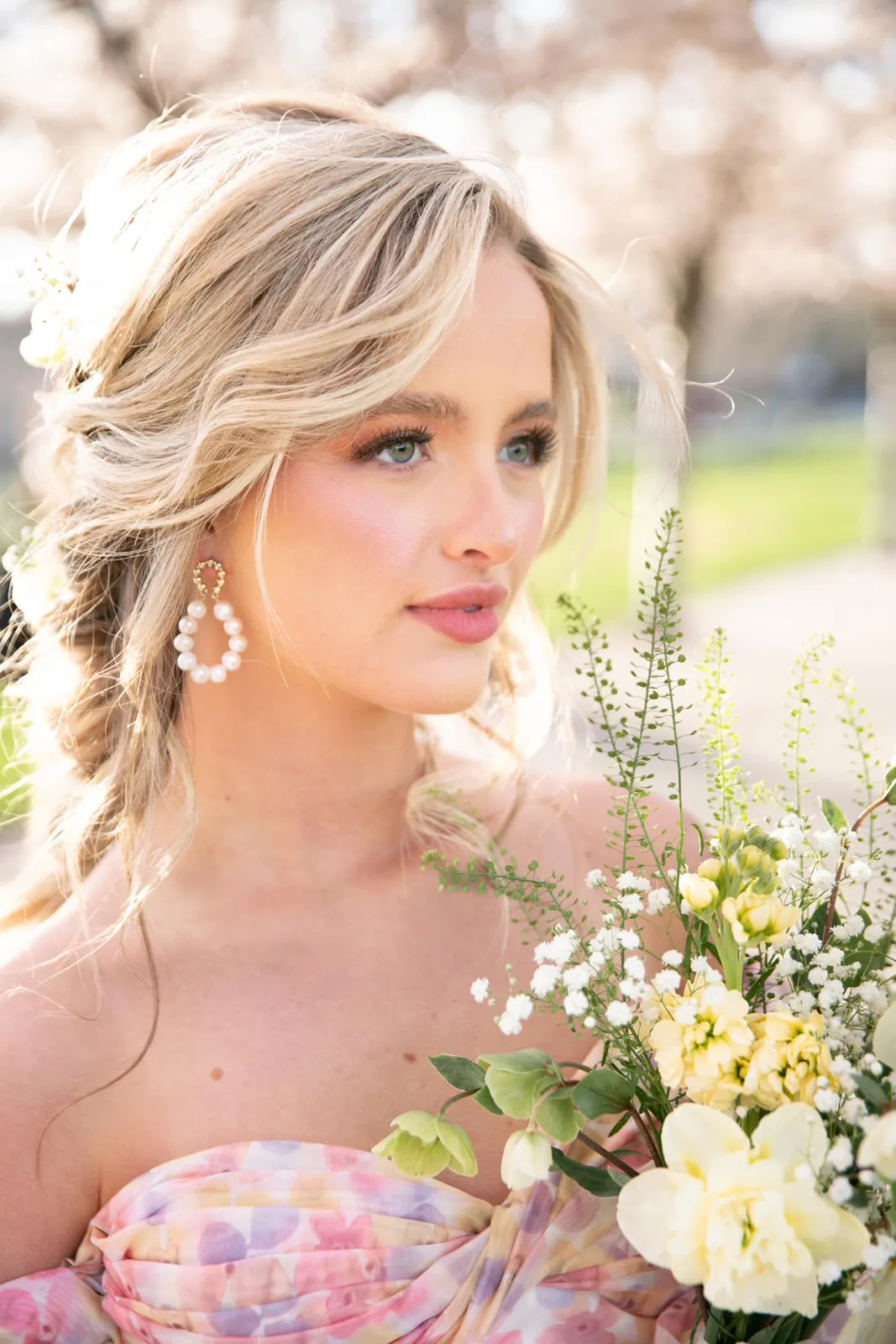 Blonde bride with soft romantic makeup and loose curls holding a spring bouquet