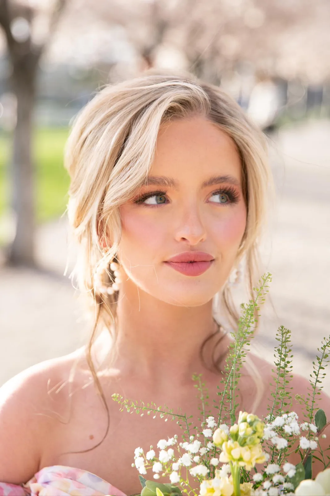 Bridal portrait with glowing skin and soft curls in front of spring blossoms