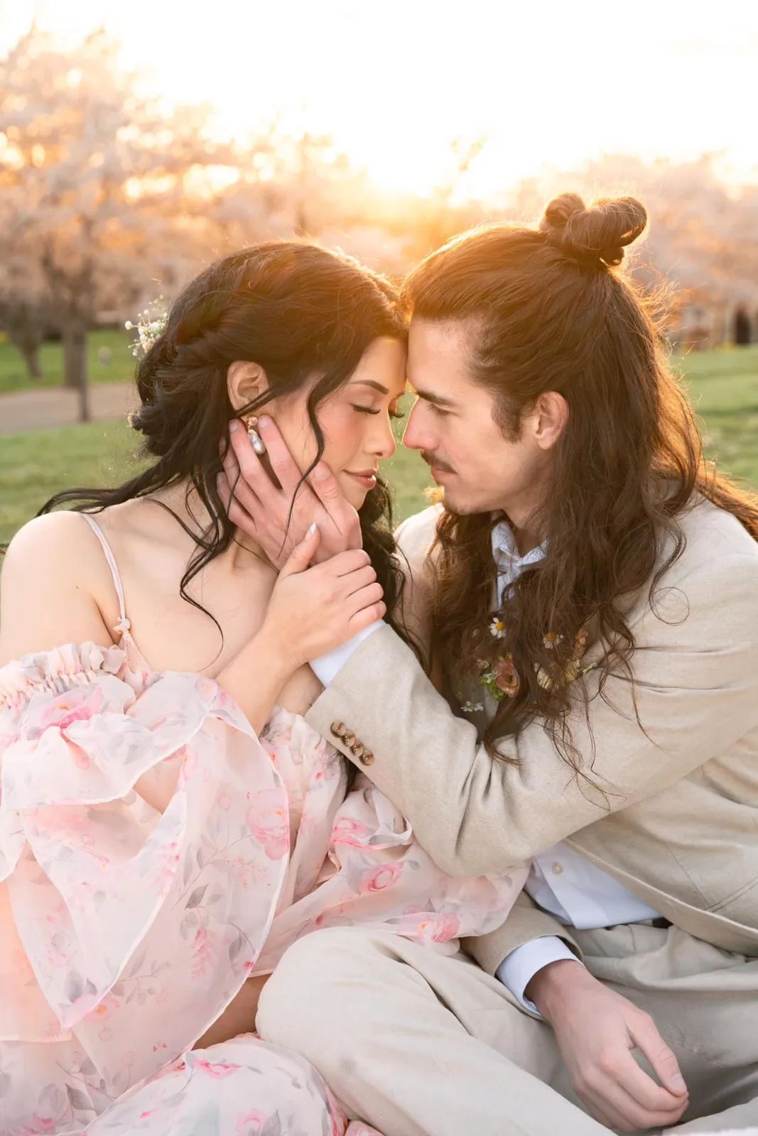 Engaged couple among cherry blossoms, bride with soft glam makeup and long waves