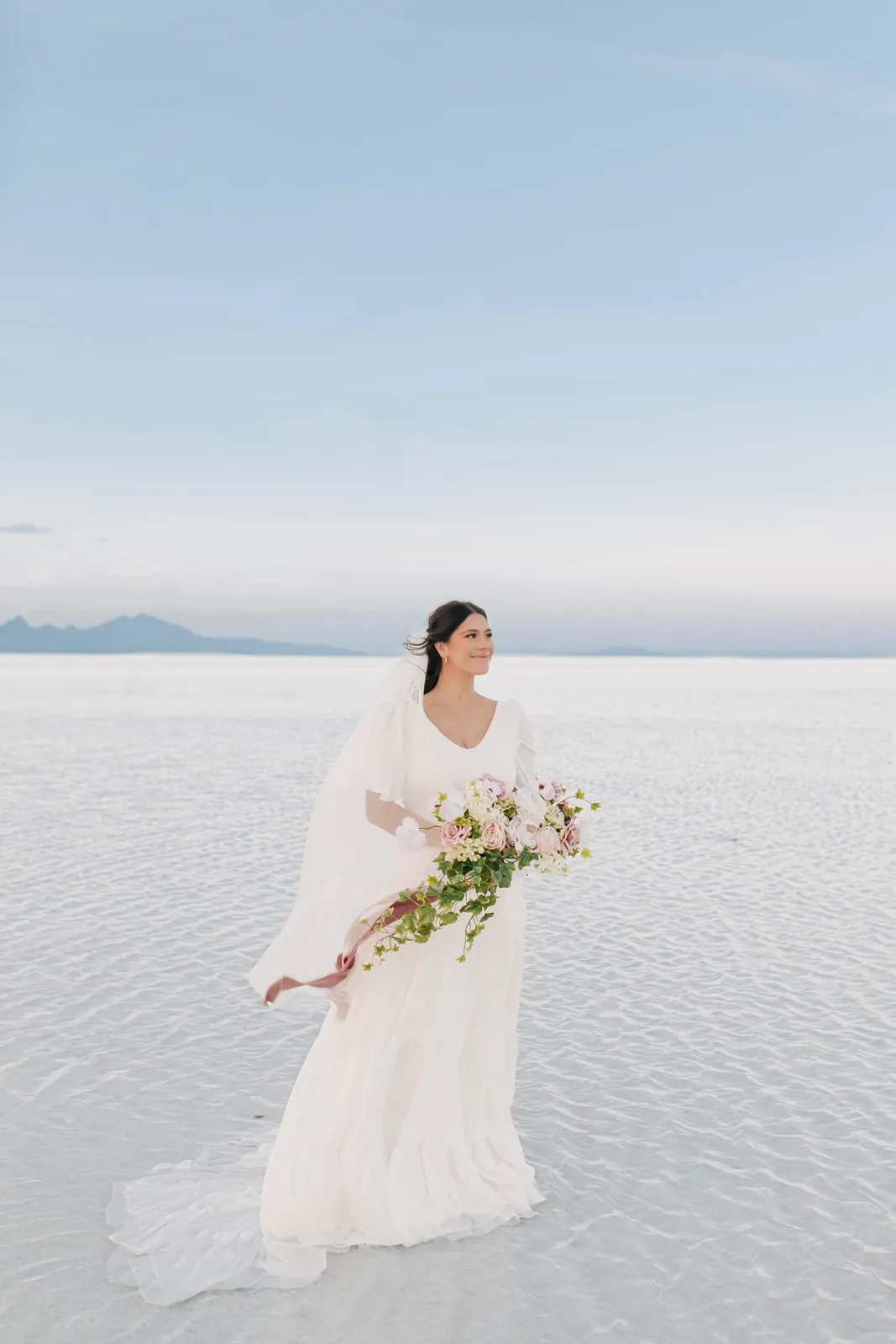 Bride in a flowing gown holding flowers on the Utah salt flats
