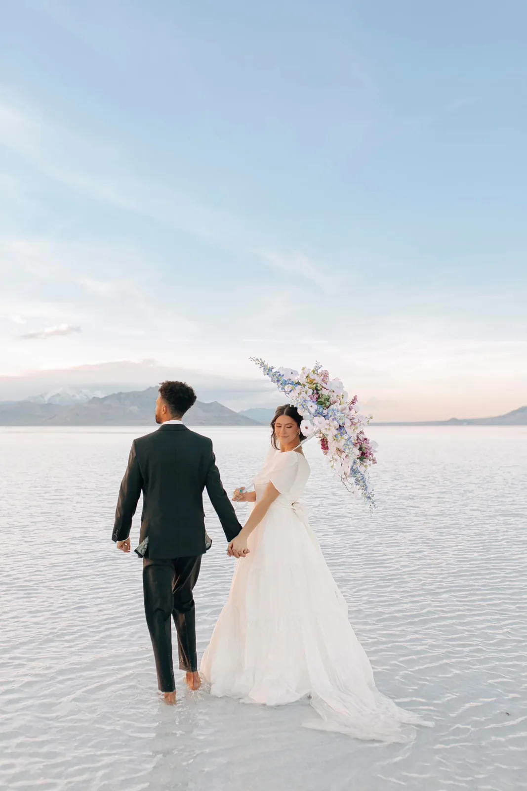 Bride and groom walking hand in hand on the Utah salt flats